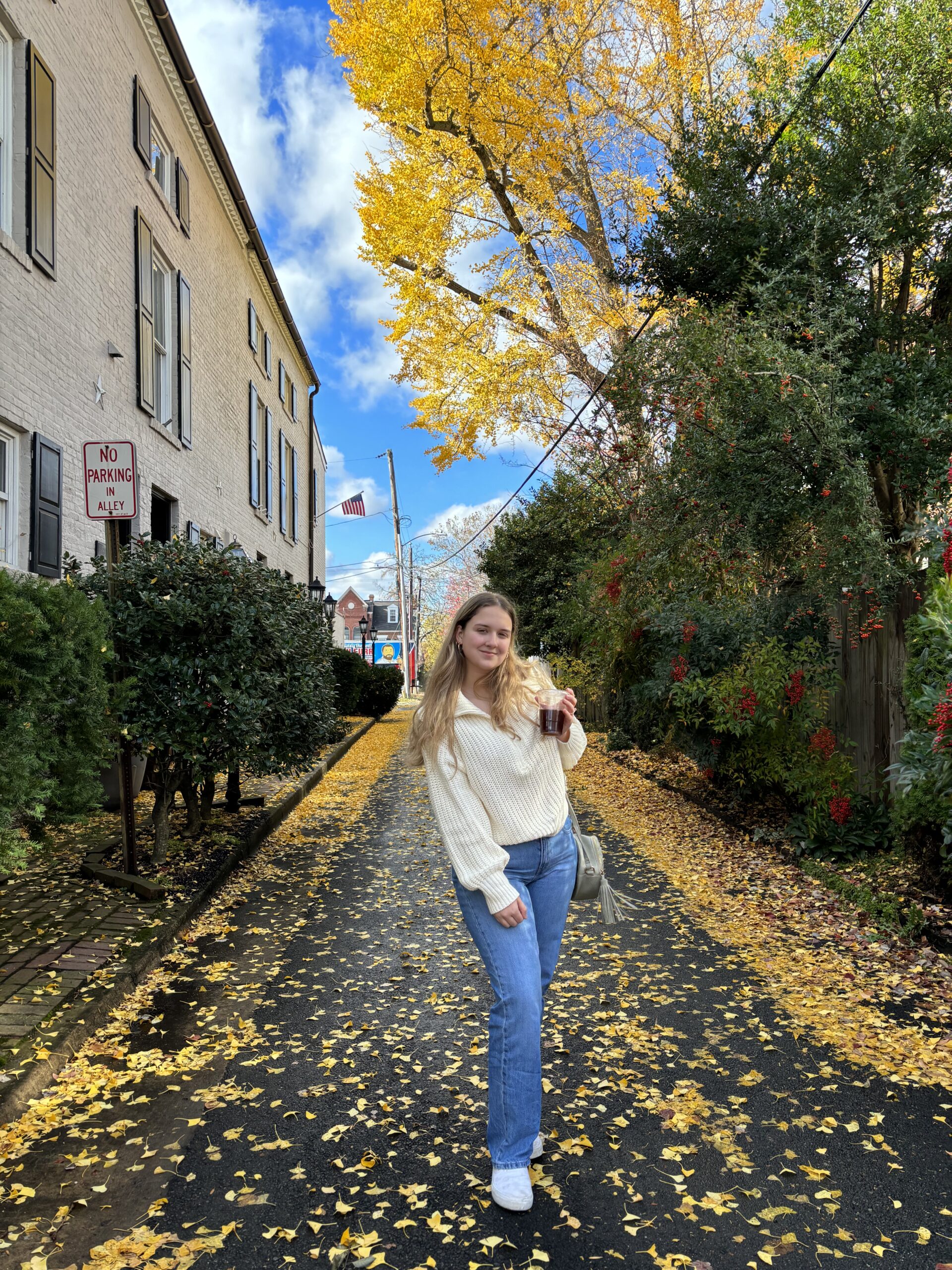 Photo of blonde girl standing in a fall street holding a coffee